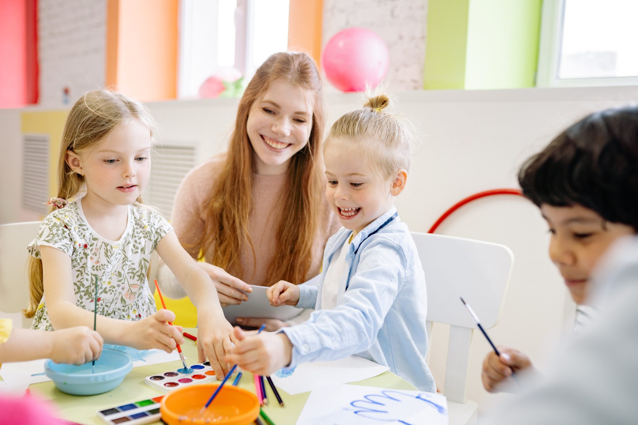 Preschool children painting with watercolors with their teacher