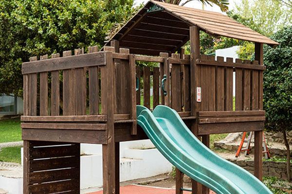 Wooden playground structure with a slide at Colégio da Beloura preschool.