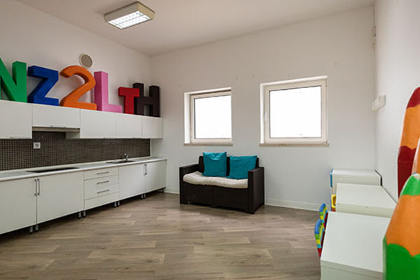 Preschool classroom with colorful letters, white cabinets, and a small couch.