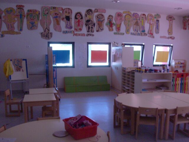 Preschool classroom with child-sized tables and chairs, and student artwork on the walls