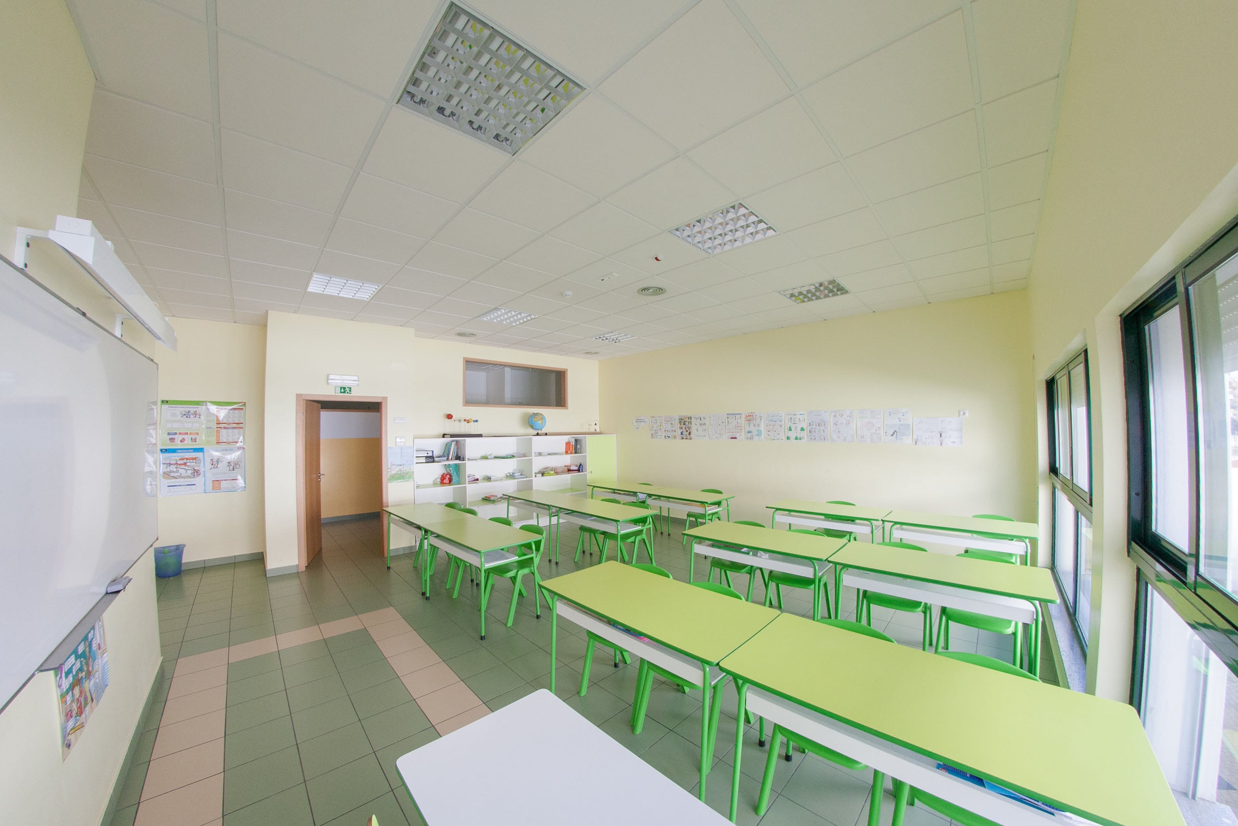 Bright and spacious classroom at Colegio A Quinta preschool with green desks and chairs, ready for students.
