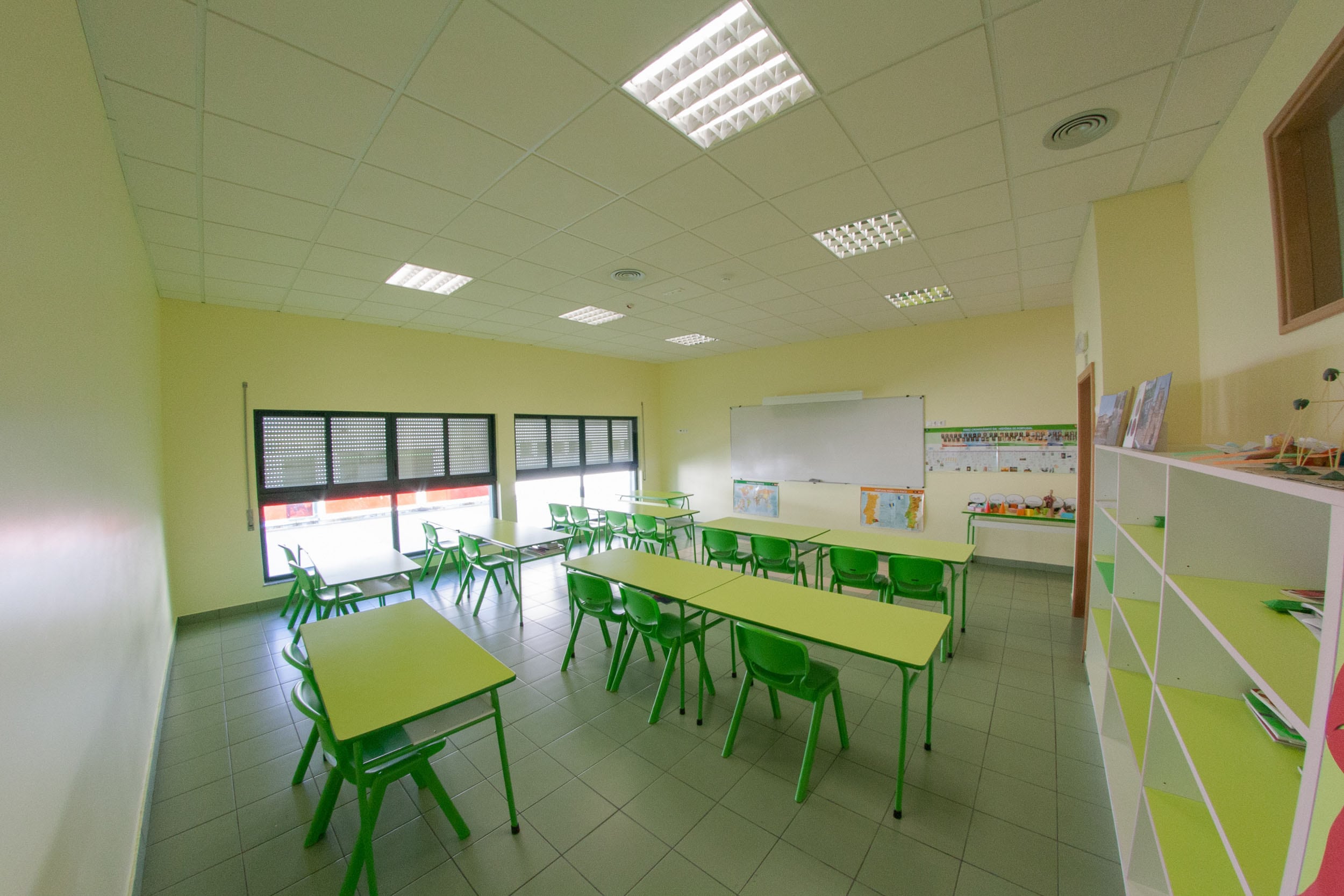 Empty classroom with green tables and chairs, ready for preschool students