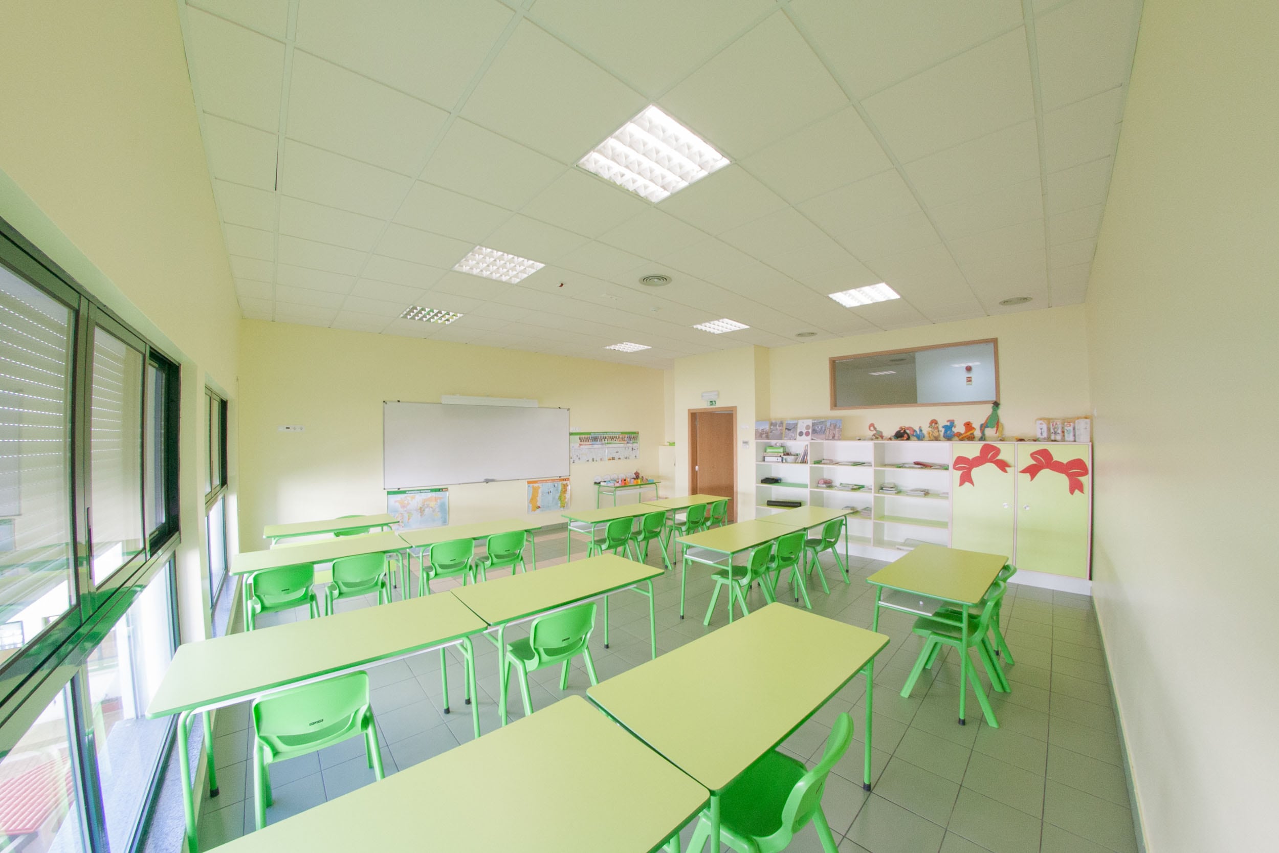 Bright and spacious preschool classroom with green tables and chairs, ready for learning.