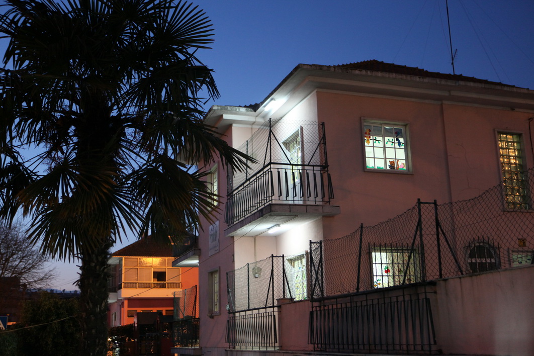 Exterior view of Canteiro dos Sonhos preschool at night, showing the building's facade and a palm tree.