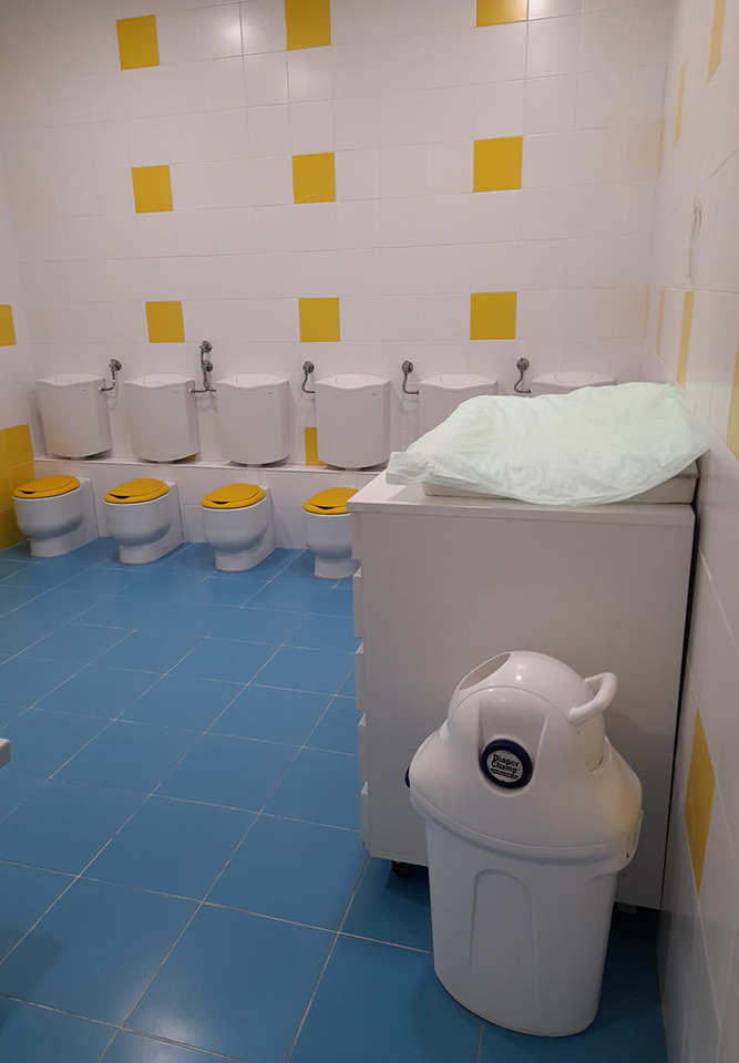 Preschool bathroom with child-sized toilets and a diaper changing station