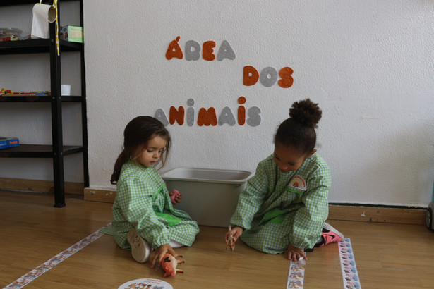 Two preschool children playing with animal toys in a classroom