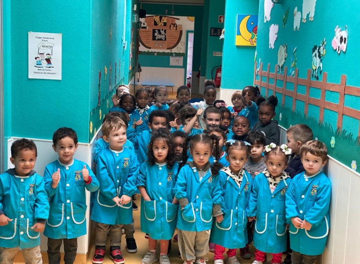Preschool children in blue coats lined up in a hallway