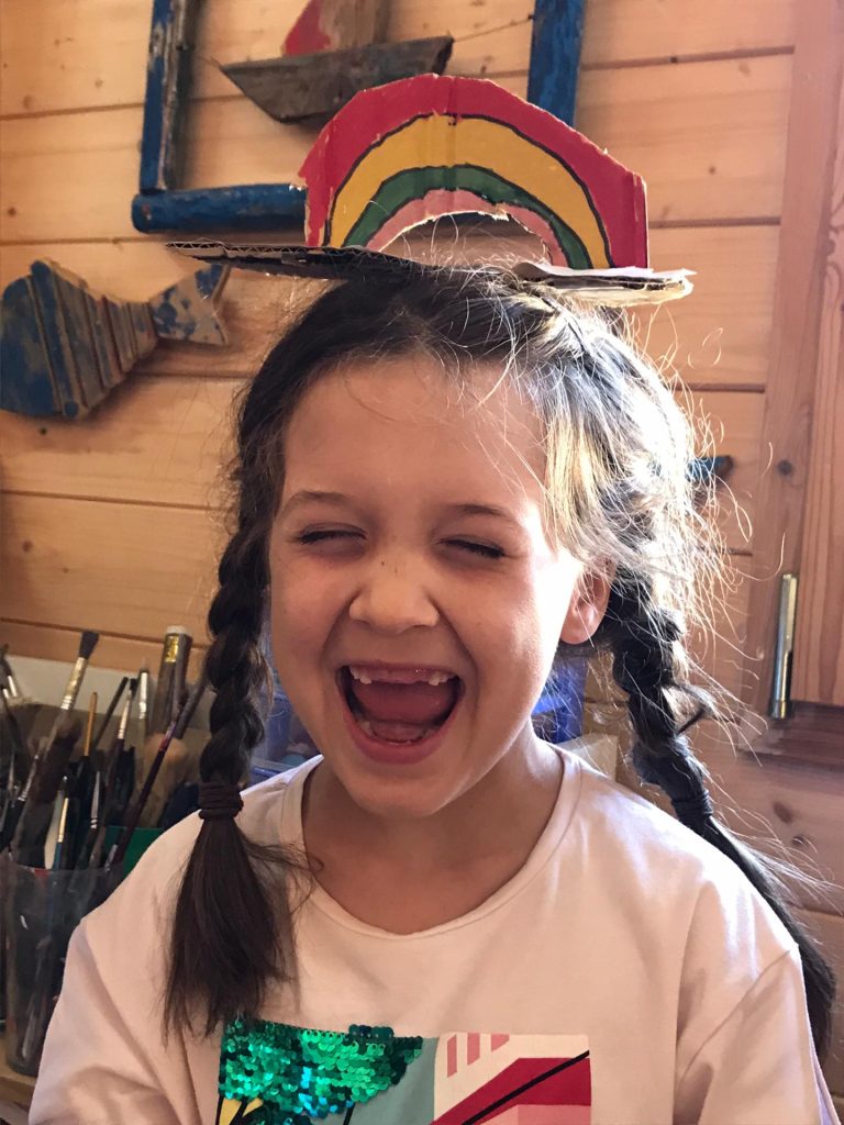 Preschool student wearing a handmade rainbow hat