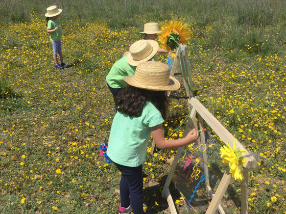 Preschool children painting outdoors in a field of flowers