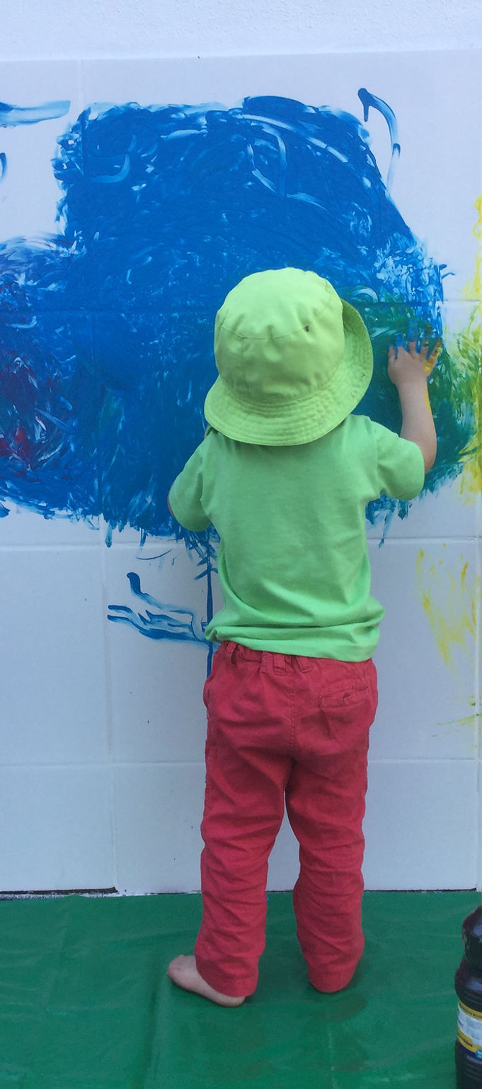 Preschool child painting on a wall