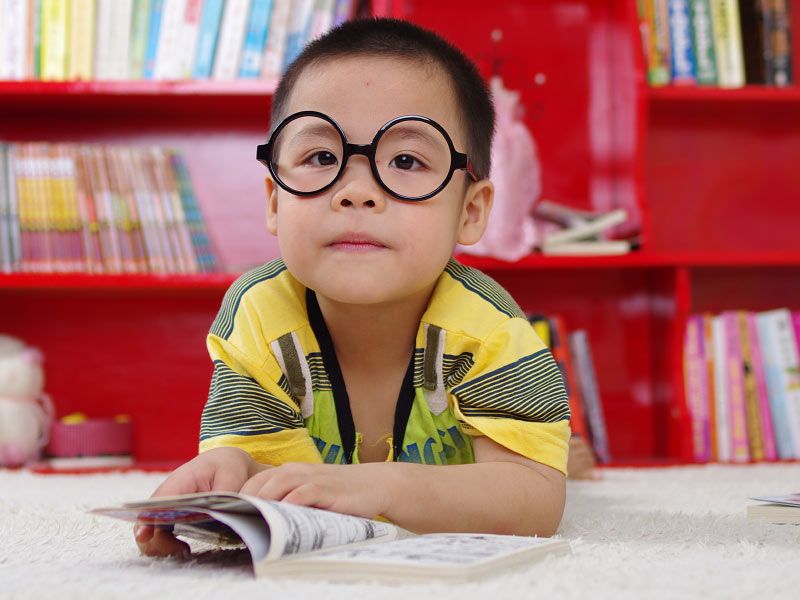 Preschool child wearing glasses reading a book