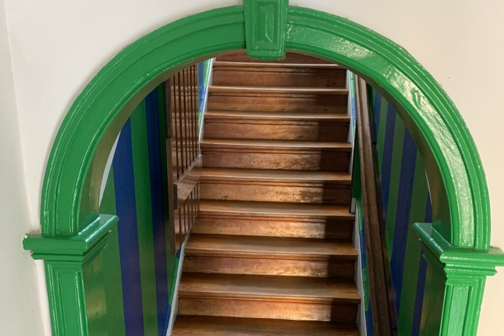 Green archway and wooden staircase inside Externato Miguel Ângelo school