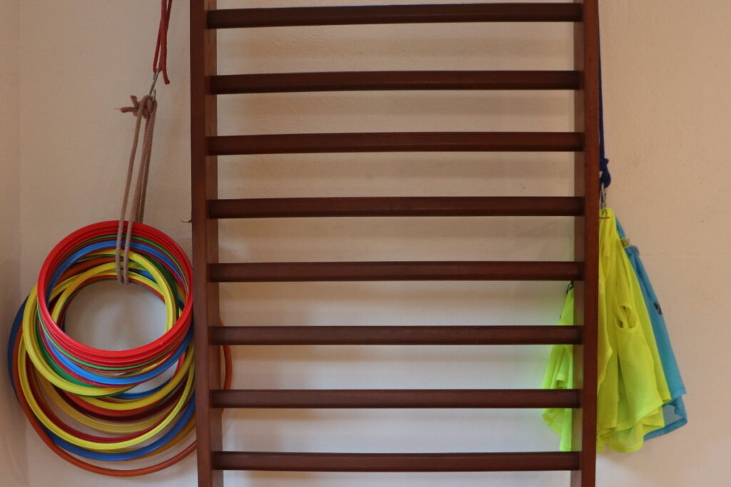 Colorful hoops and shirts hanging on a wooden wall ladder in a preschool classroom