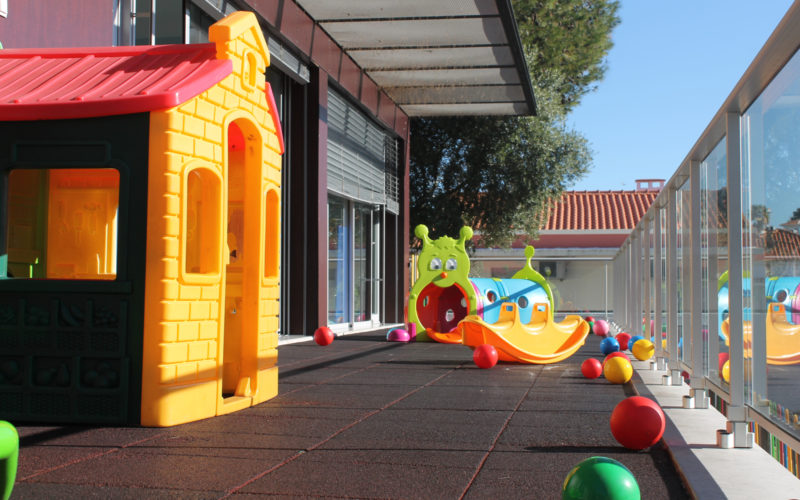 Outdoor playground area at Creche da Pampilheira preschool with colorful play structures and balls.