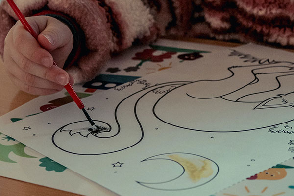 Preschool child painting a picture of a sleeping fox and moon