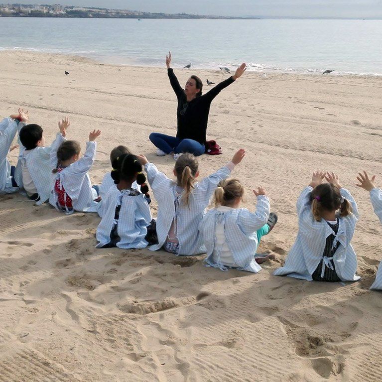 Preschool children and teacher practicing yoga or stretching exercises on the beach