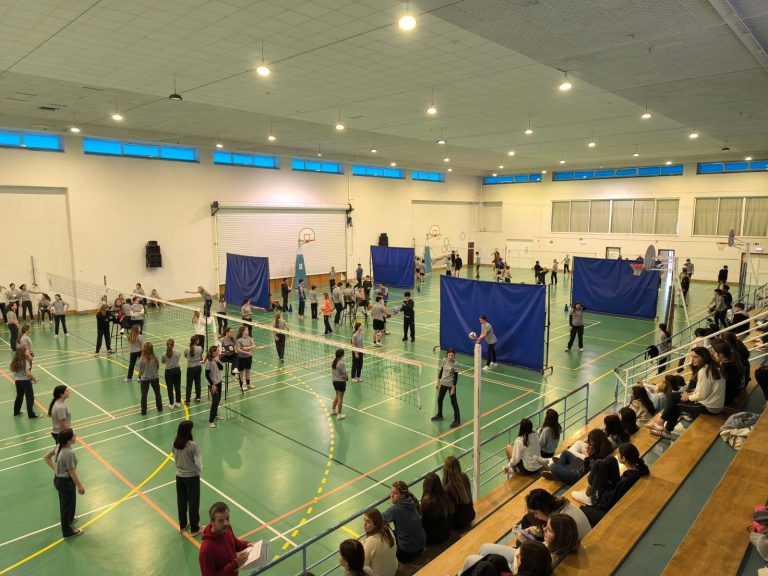 Students playing volleyball in a school gymnasium