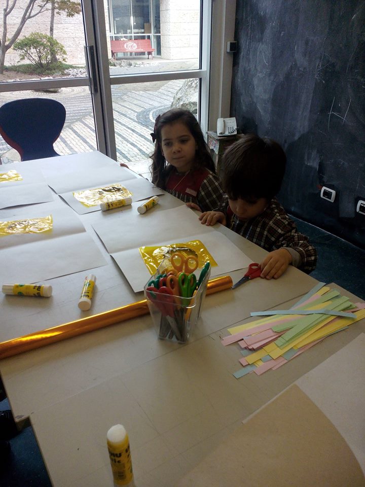 Preschool children participate in an art and craft activity, using scissors and glue to create colorful paper projects.