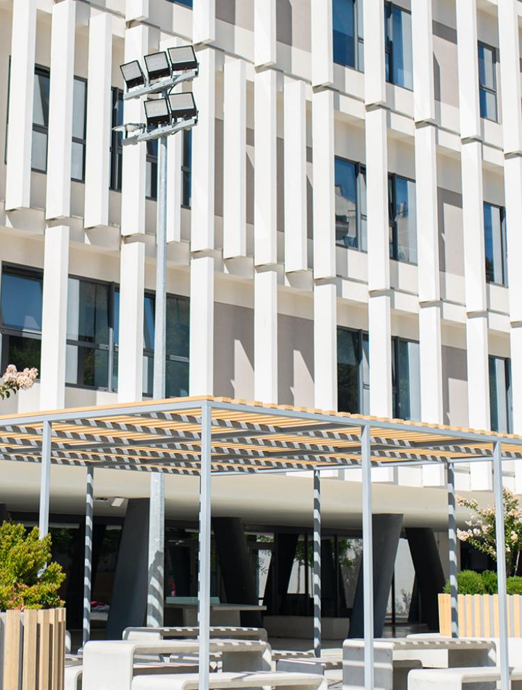 Exterior view of PaRK International School Alfragide Senior School, showcasing modern architecture with a pergola and outdoor seating area.