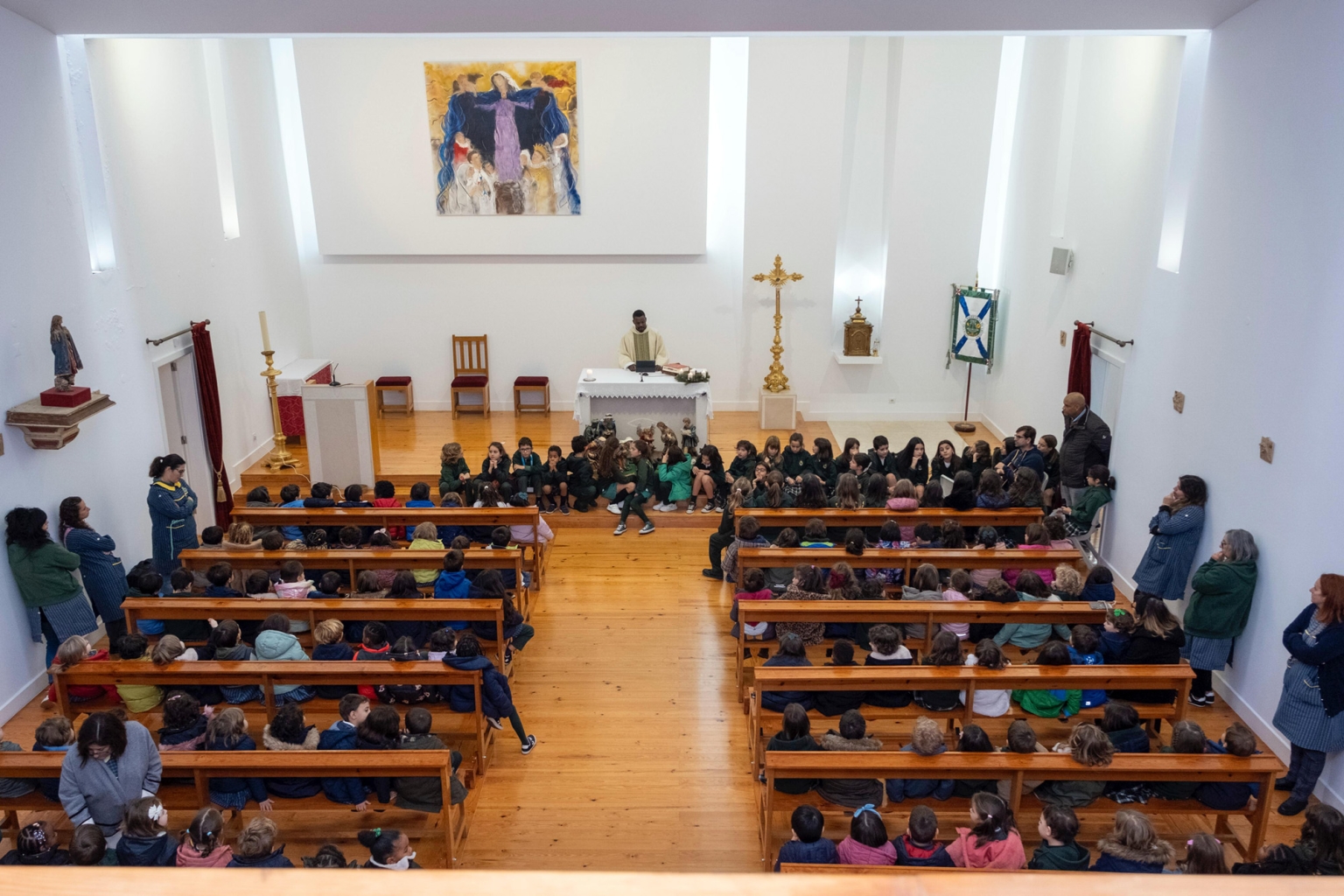 Preschool children sitting in pews in a church during a school assembly.