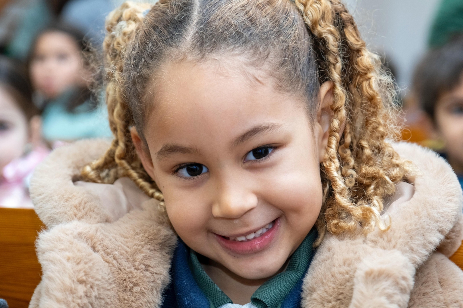 Happy preschool student with curly hair smiling at the camera