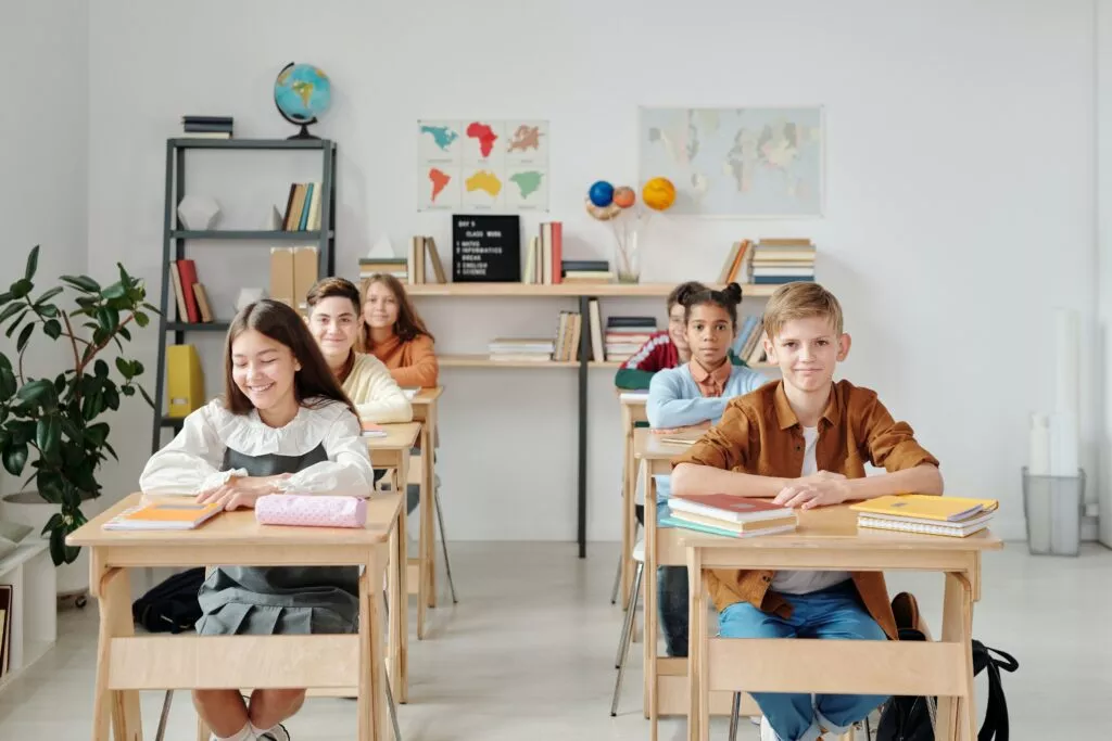 Happy students sitting at desks in a classroom
