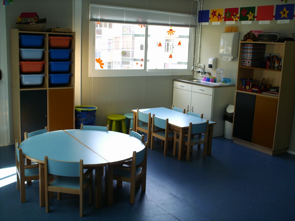 Preschool classroom with tables, chairs, and storage units