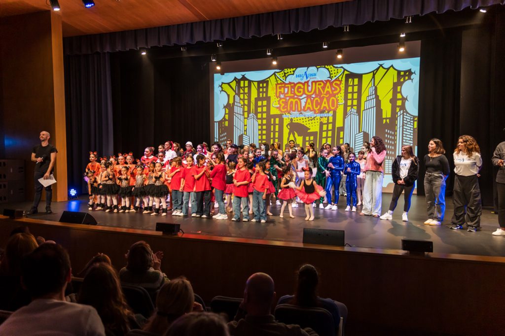 Preschool children in red shirts performing on stage