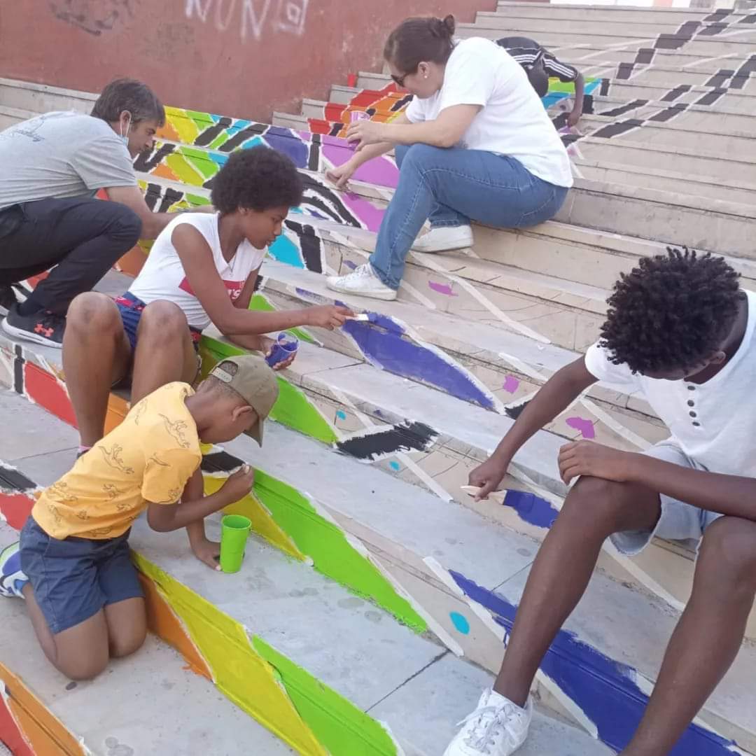 Children and adults painting a colorful mural on a set of stairs