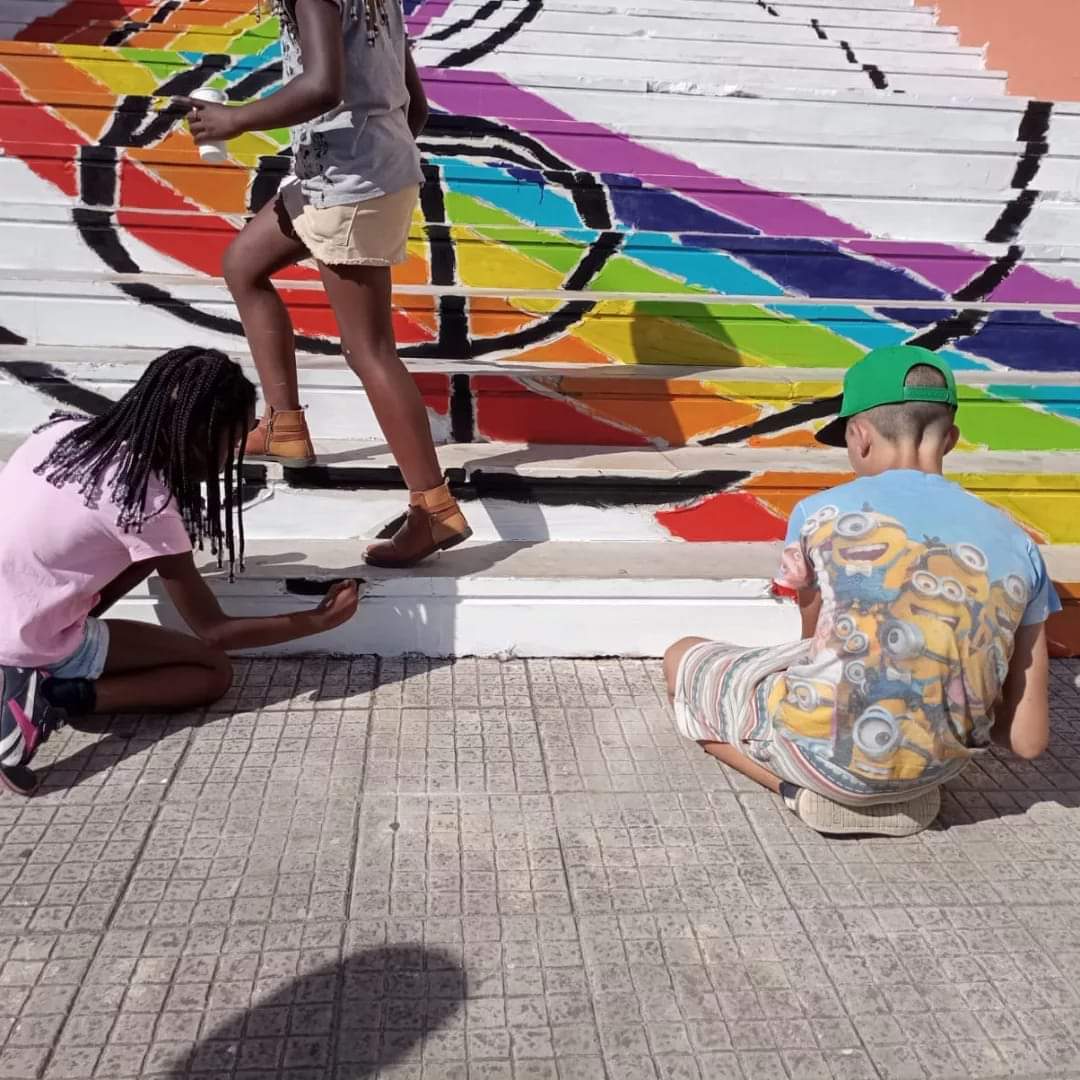 Children painting a rainbow mural on the school stairs