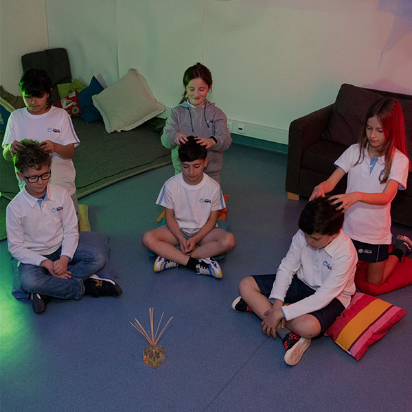 Preschool children participating in a calming activity, seated on the floor and gently massaging each other's heads.