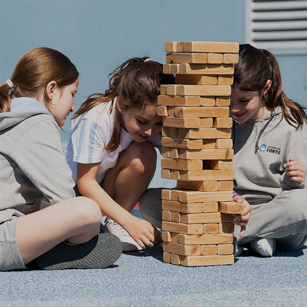 Preschool children playing a giant Jenga game outdoors