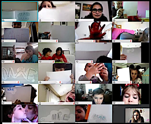 Preschool children participating in a virtual Mother's Day event, holding signs that say "Mãe"