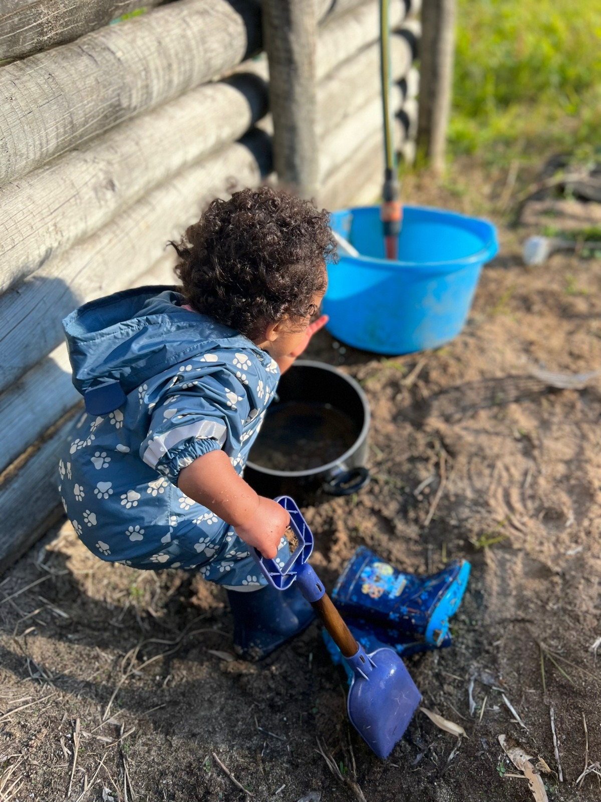 Toddler playing with a shovel and bucket in the school's outdoor play area