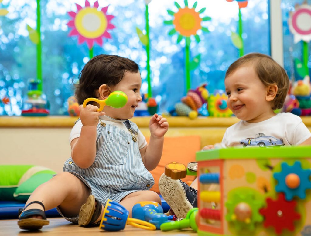 Two toddlers playing with toys at Colégio S. Francisco de Assis preschool.