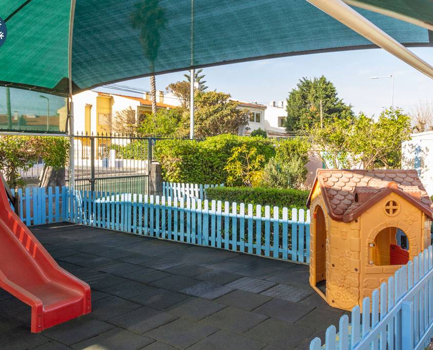 Preschool playground with a red slide and a playhouse