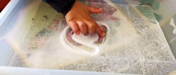 Preschool child drawing in salt