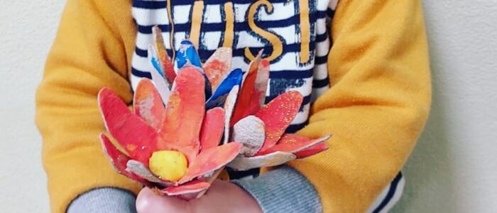 Preschool student proudly holding a handmade flower craft