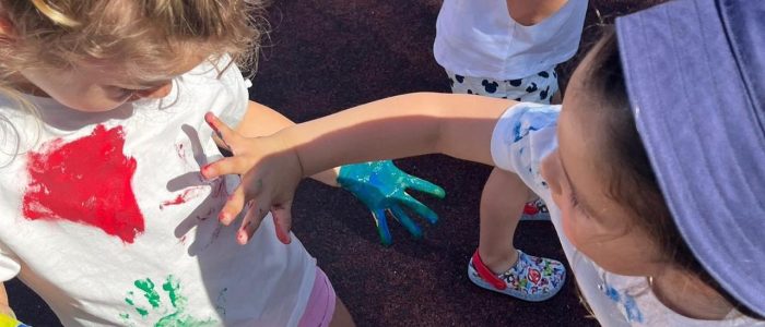 Preschool children with painted hands and shirts
