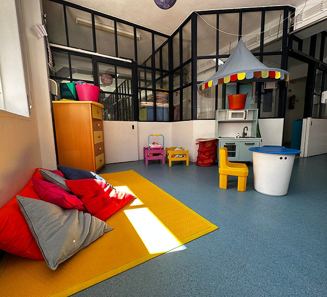Preschool play area with colorful pillows, toy kitchen, and play stroller