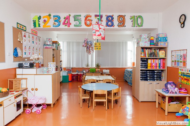 Preschool classroom with colorful decorations, tables, chairs, and learning materials