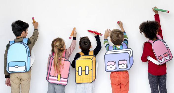 Preschool children with backpacks drawing on a wall