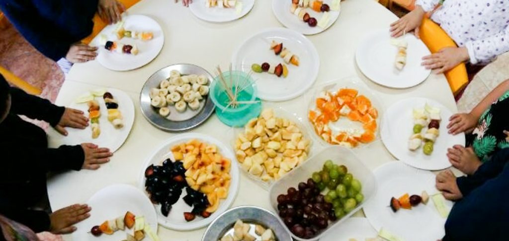 Preschool children making fruit skewers during a healthy eating activity