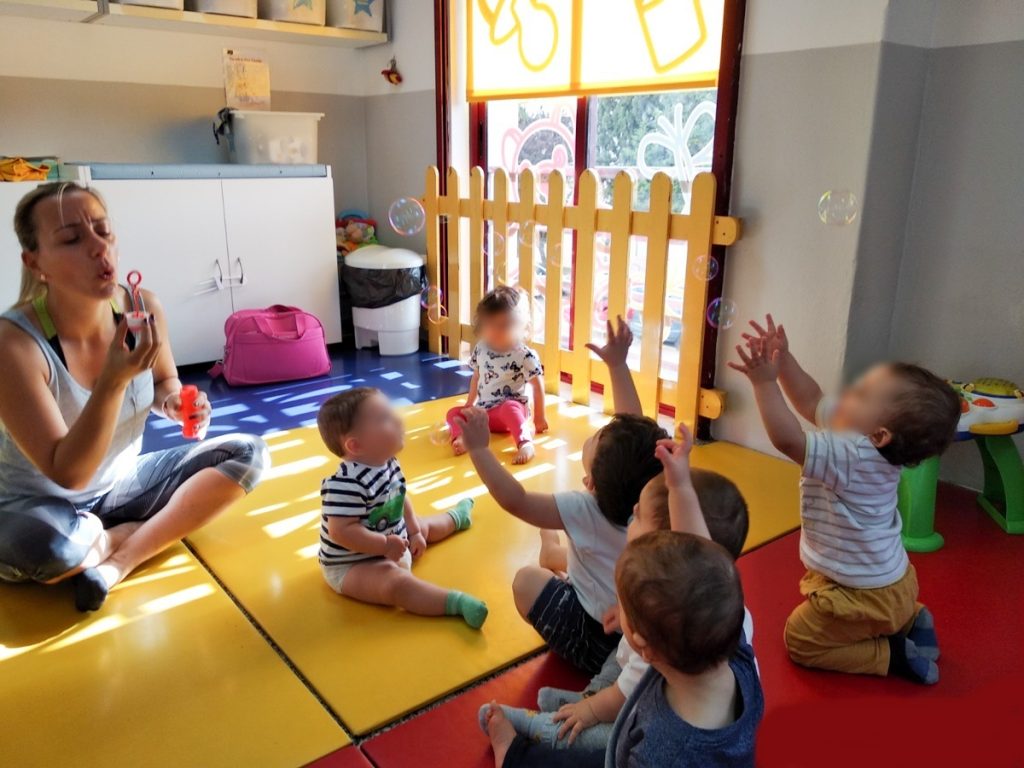 Preschool teacher blowing bubbles for children