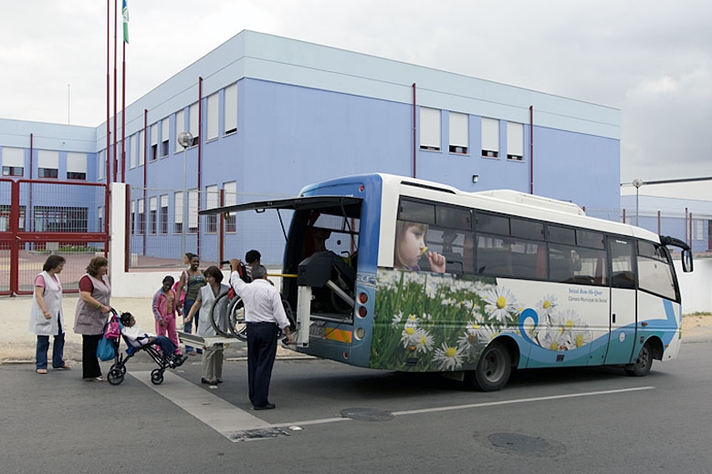 Students with disabilities are helped off of a school bus in front of Escola Básica Quinta do Conde de Portalegre.