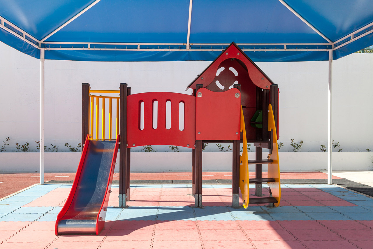 Colorful playground structure with a slide and climbing area, suitable for preschool-aged children.