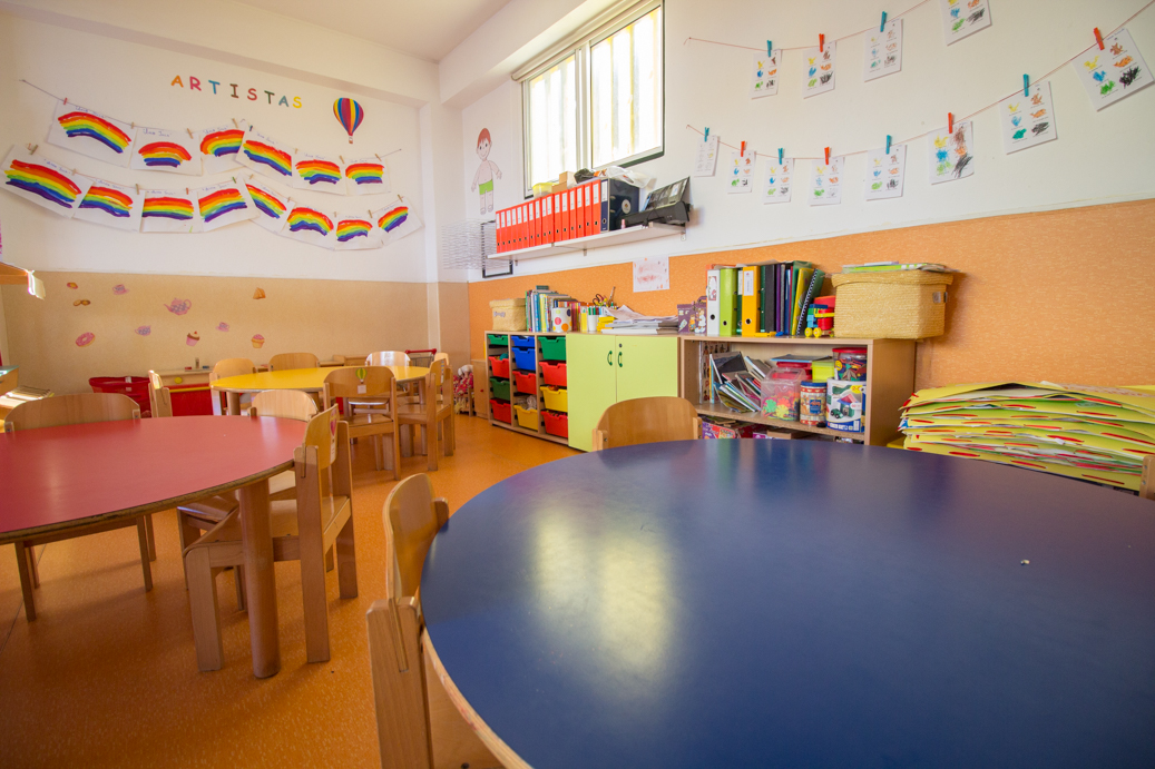 Preschool classroom with colorful tables, chairs, and children's artwork