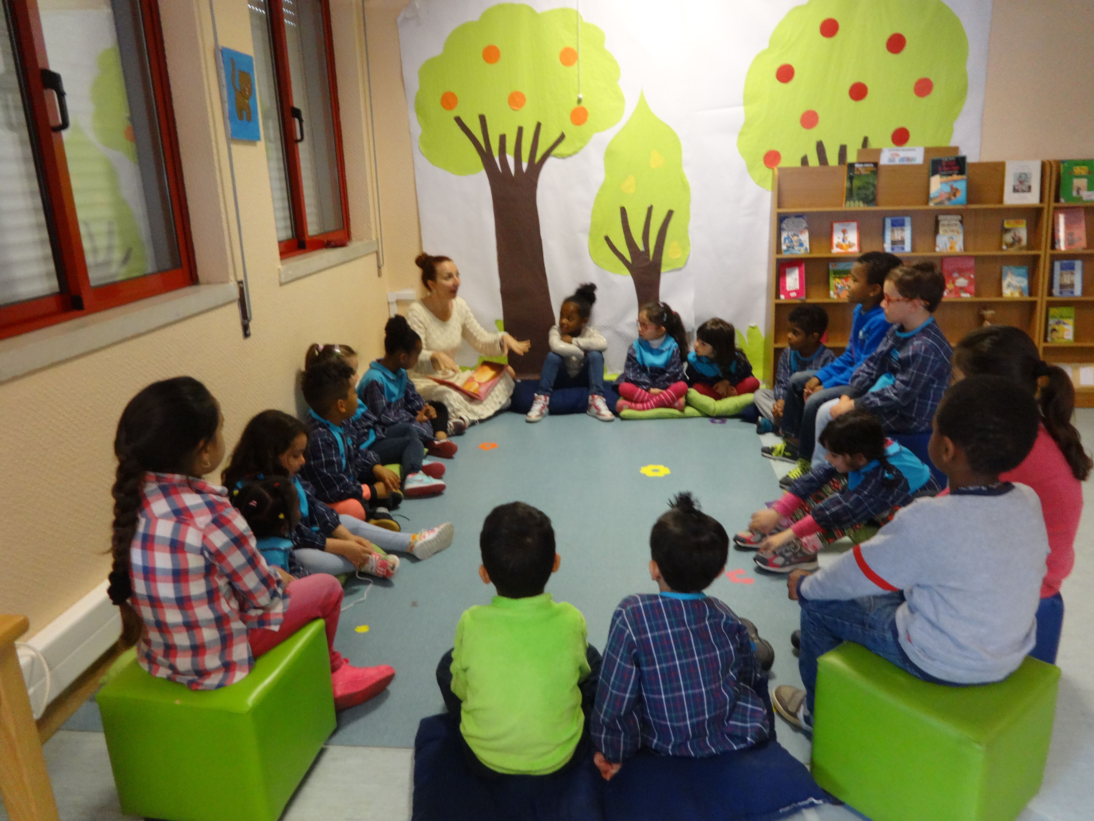 Preschool children sitting in a circle listening to a teacher read a book