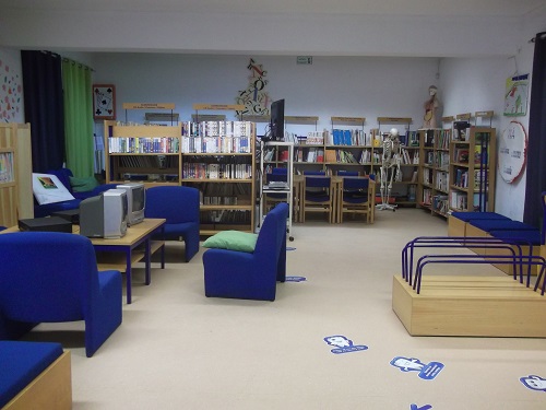 School library with bookshelves, comfortable seating, and a skeleton model.