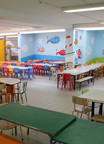 Preschool cafeteria with colorful tables and chairs, and a mural of fish on the wall